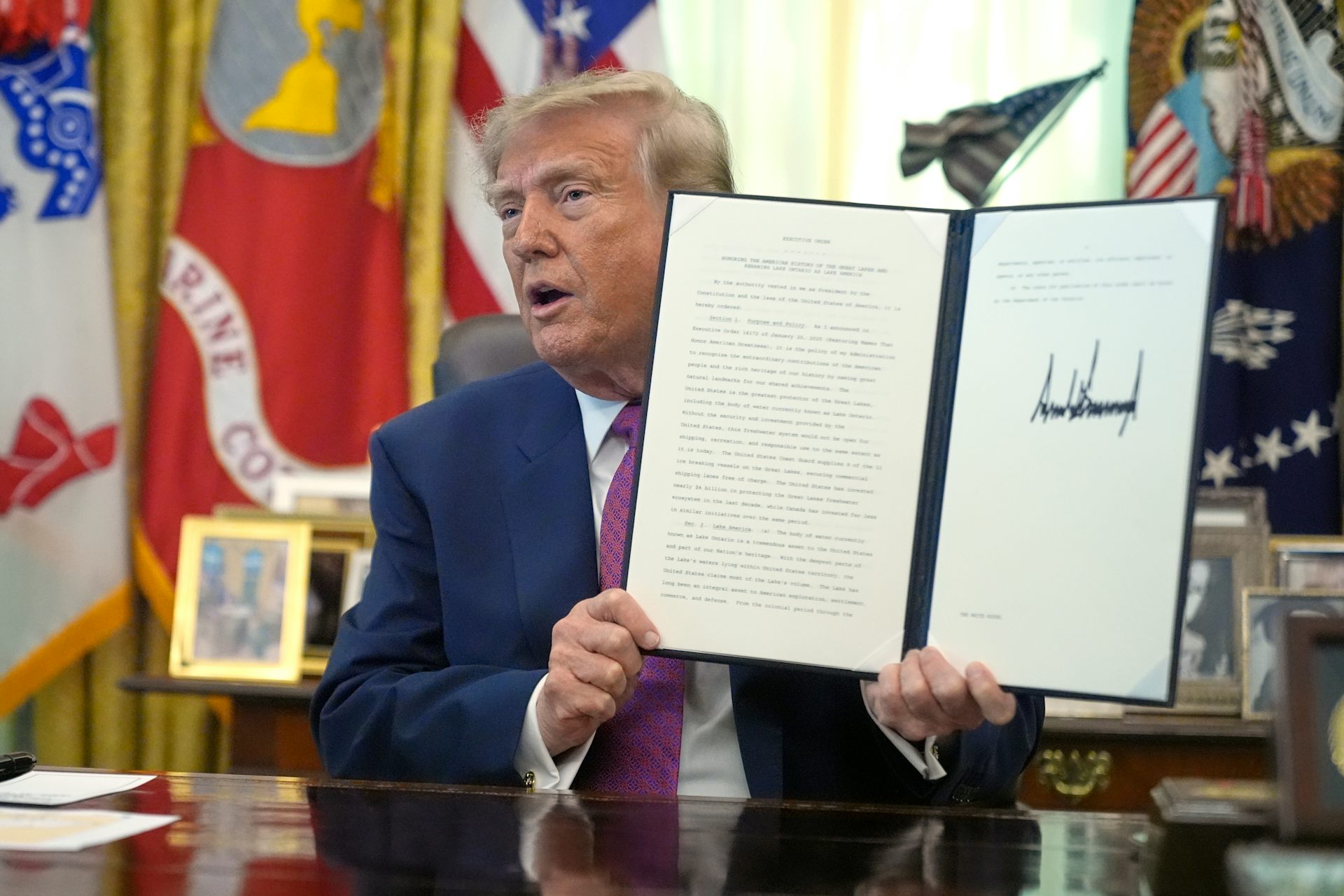 Le président Donald Trump brandit un décret signé dans le Bureau ovale de la Maison-Blanche