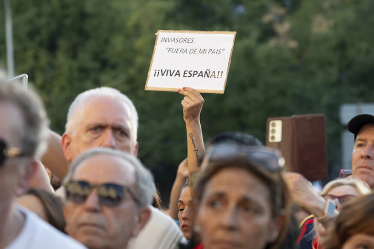 Manifestación. Una mano sujeta una consigna: "Invasores, fuera de mi país"