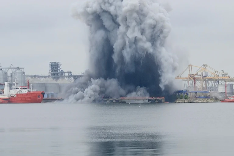 A large grey cloud from an explosion over a port