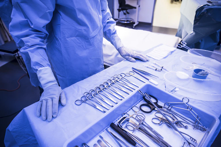 Surgeon in front of operating room table, with sterile equipment laid out in rows