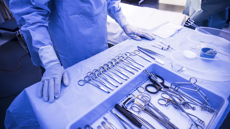 Surgeon in front of operating room table, with sterile equipment laid out in rows