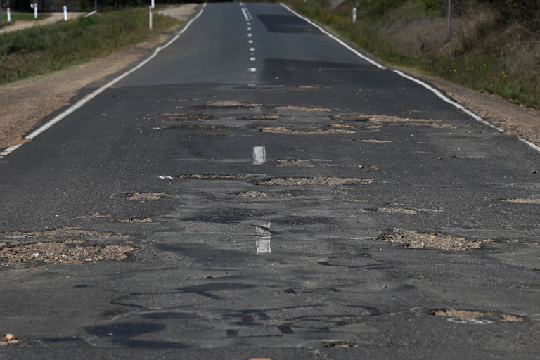 A country Victorian road is riddled with potholes.