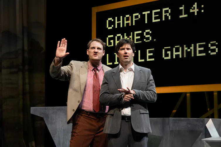 Two performers act on stage during a play.