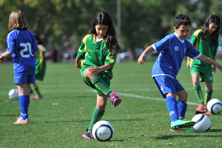 Children practising soccer skills in open field.