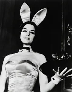 A woman in a Playboy Bunny costume, holding a tray of drinks