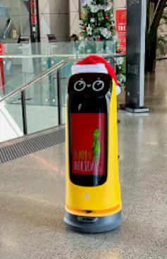 A yellow kettybot wearing a Christmas hat