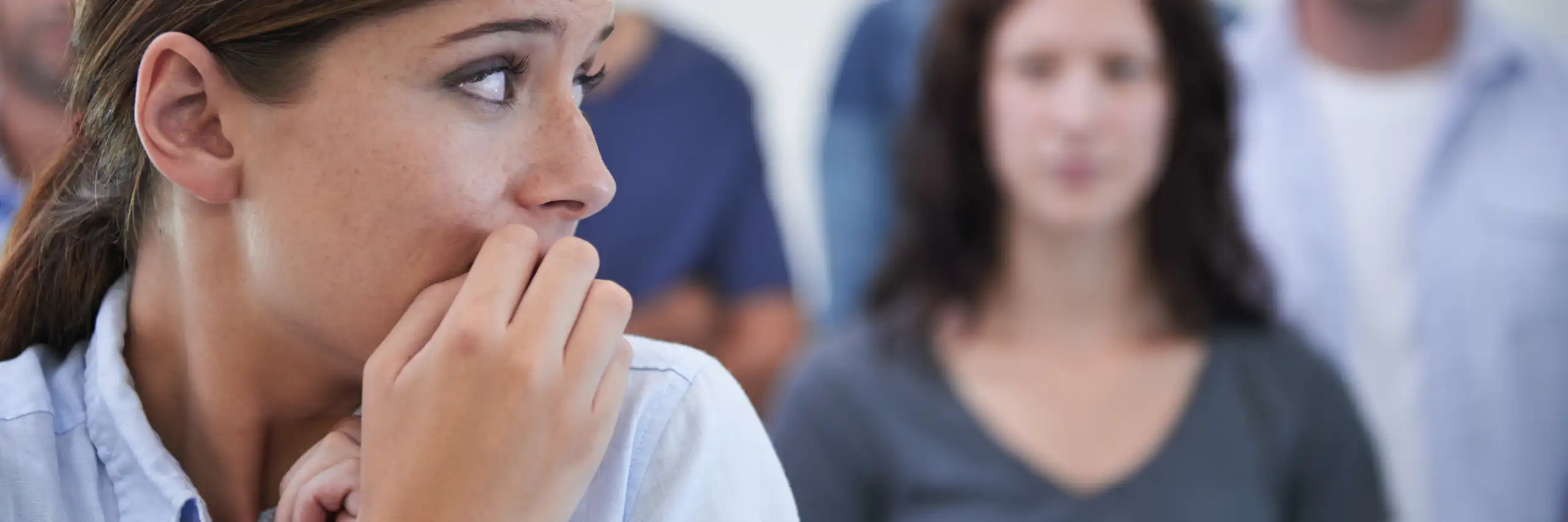 Femme se rongeant les ongles de honte devant es collègues