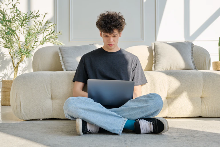 Man sitting on floor looking at laptop.