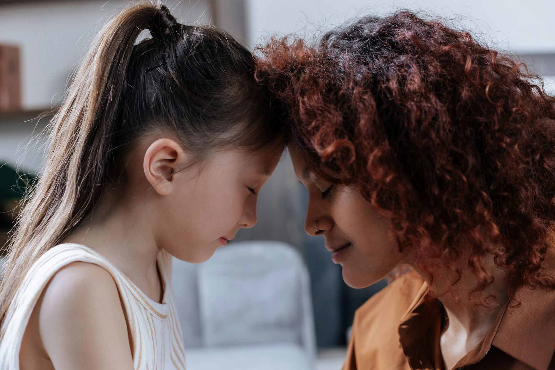 A parent and child touching foreheads and both look calm.