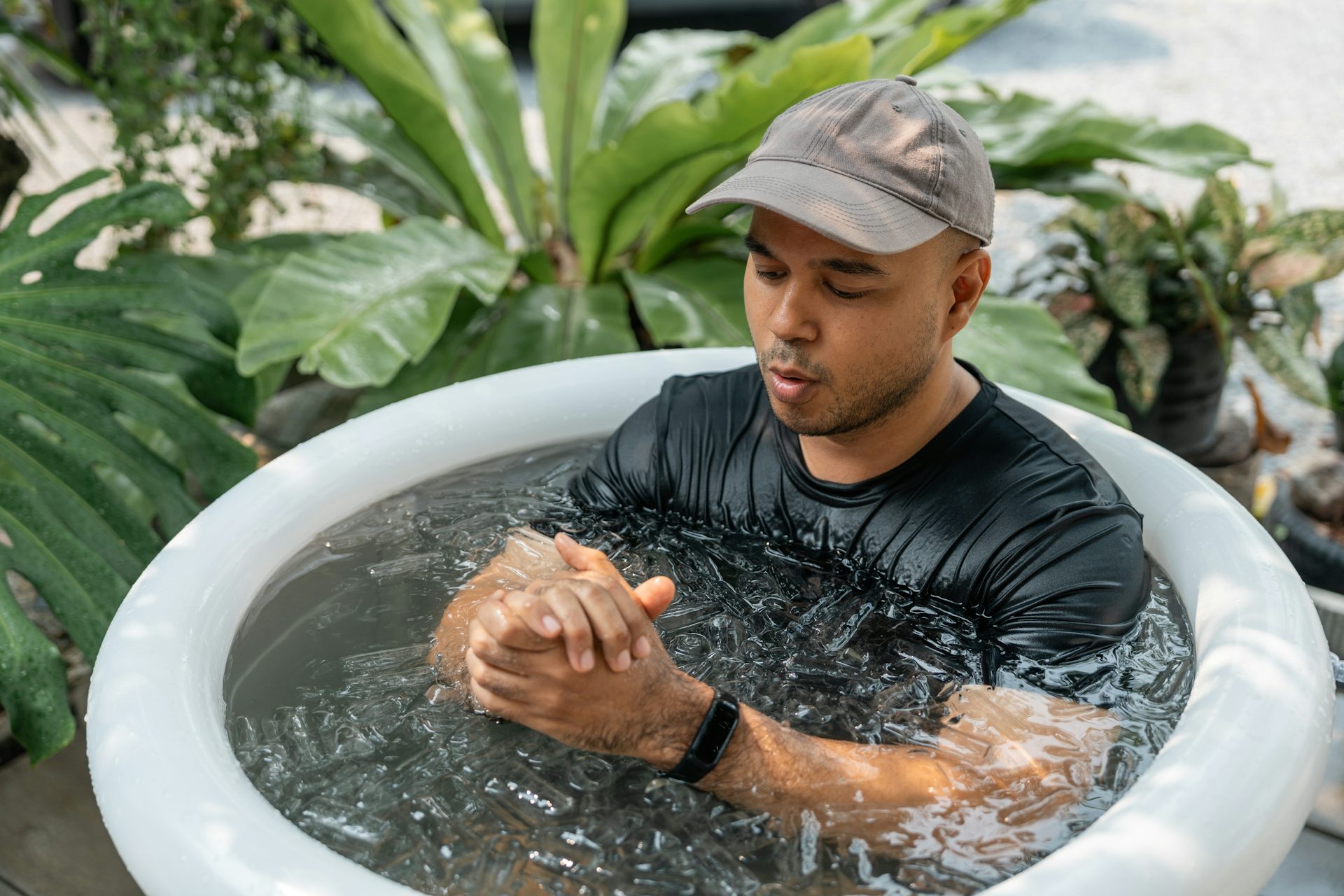 Um homem sentado em um banho de gelo olha para o smartwatch que está no pulso.