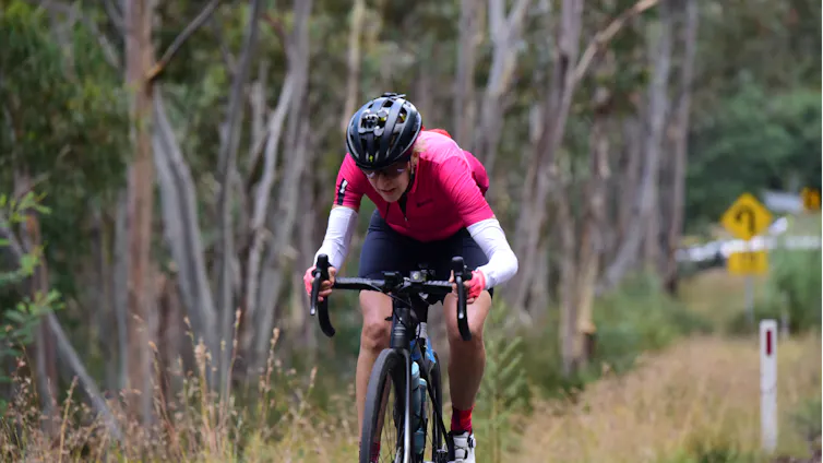 A woman in her late fifties cycling on a bush road