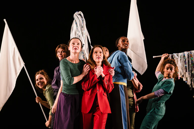 Cast of a play with white props and a black background