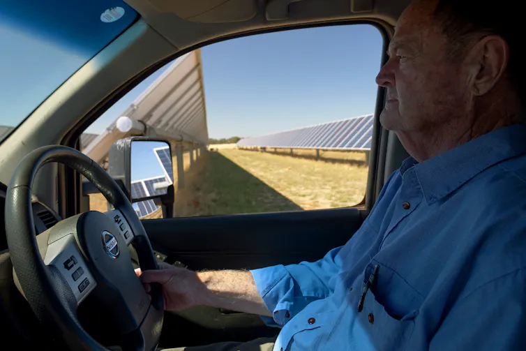 farmer driving past solar panels on his farm.