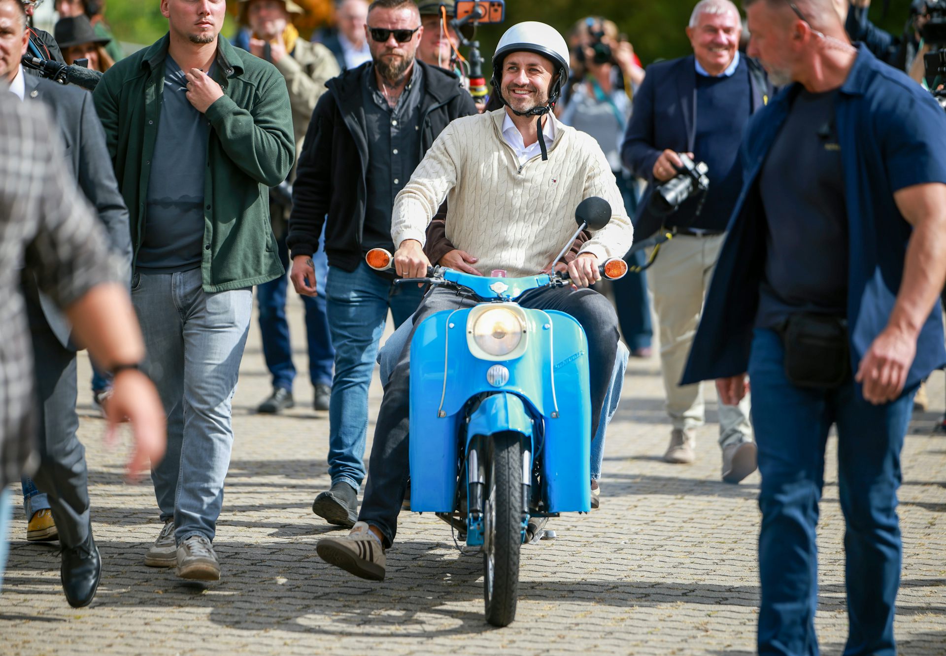 Ulrich Siegmund riding a Simson Schwalbe motorcycle away from a polling station.