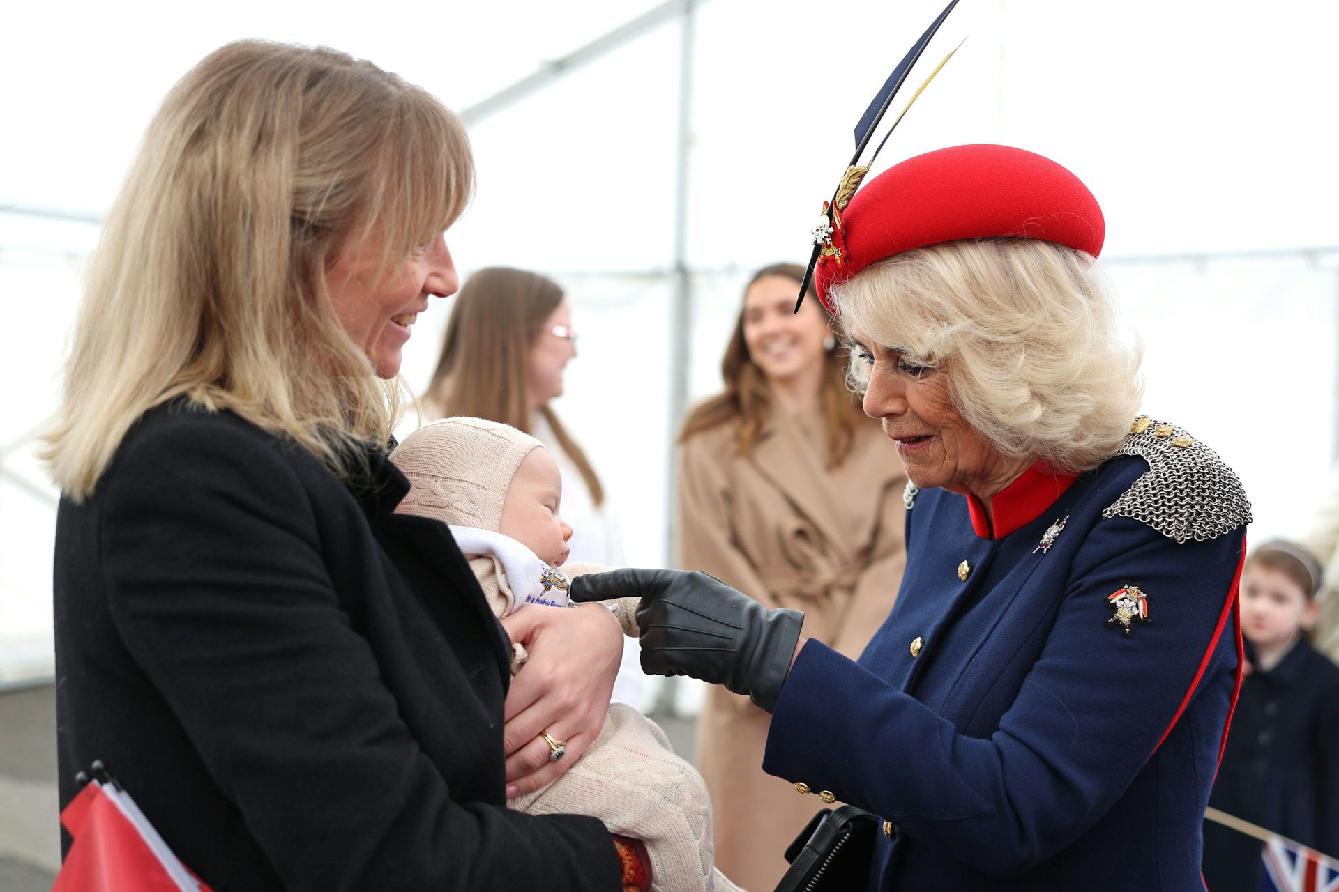 Queen Camilla pokes finger at baby held by smiling woman
