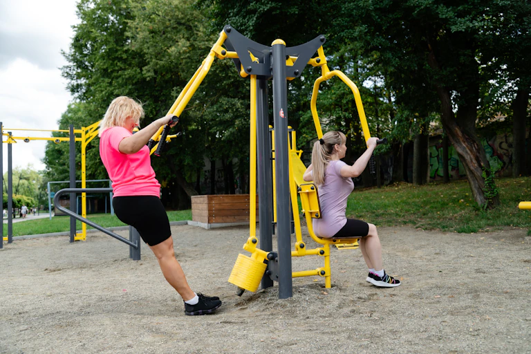 Dos mujeres haciendo ejercicio en un parque con aparatos.