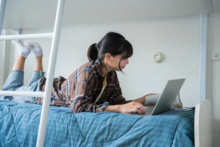 Young woman looking at laptop on bed