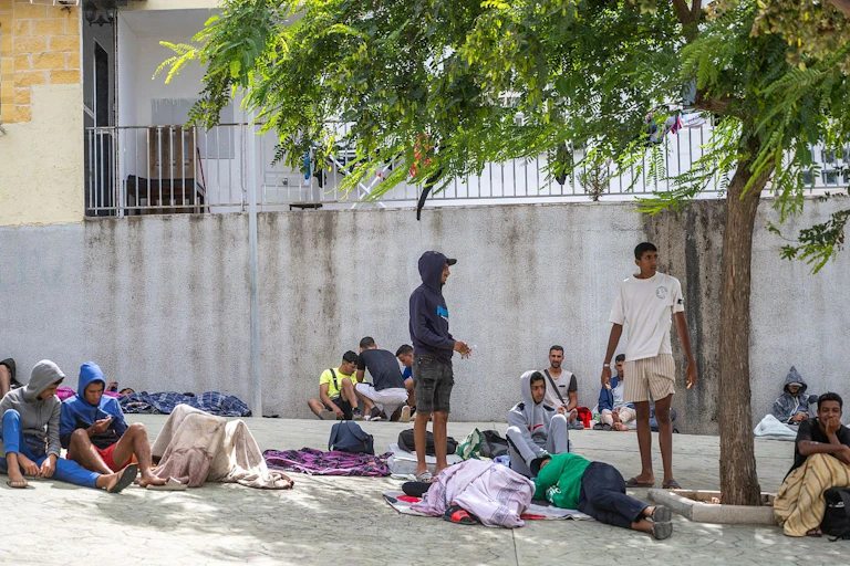 Jovenes deambulando, sentados y tumbados en una calle.
