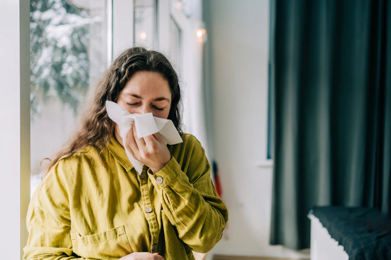 A woman sneezes into a tissue