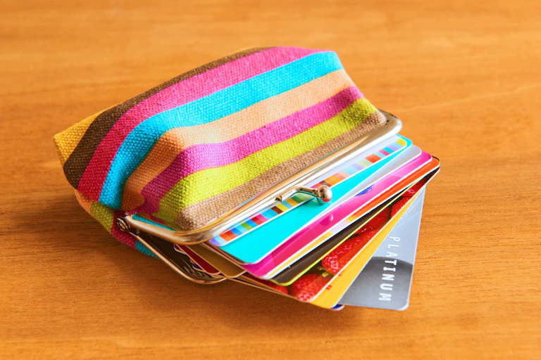 A colourful purse filled with lots of plastic bank cards and loyalty cards.