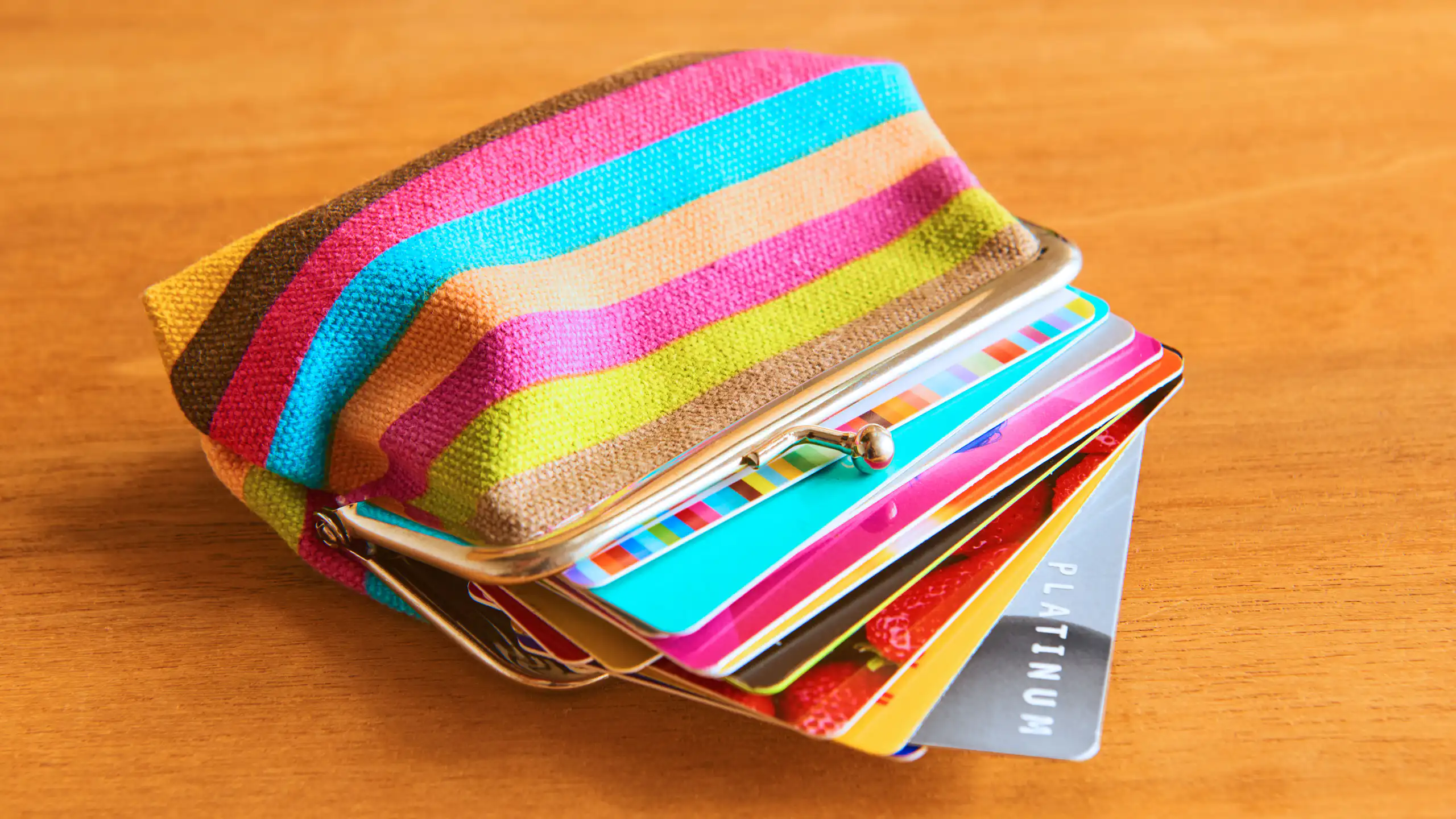 A colourful purse filled with lots of plastic bank cards and loyalty cards.