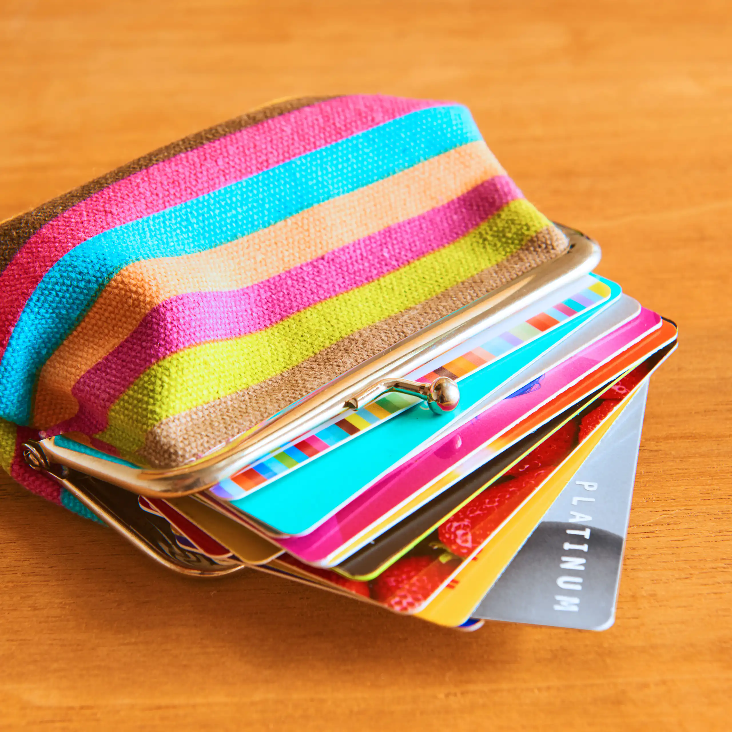 A colourful purse filled with lots of plastic bank cards and loyalty cards.