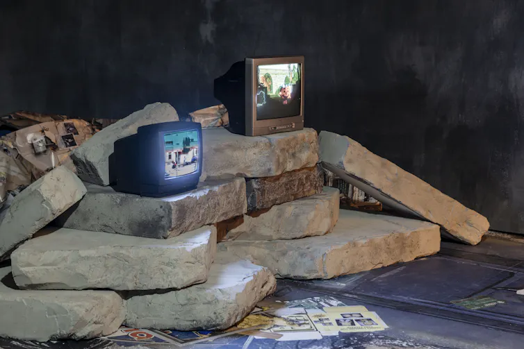 Two TVs on a haphazard stack of stone slates.