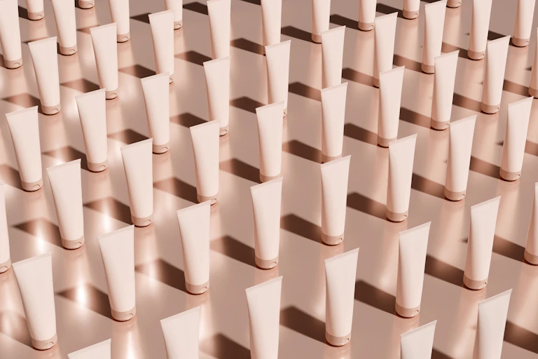 Rows of white or pale pink skincare tubes in diagonal rows
