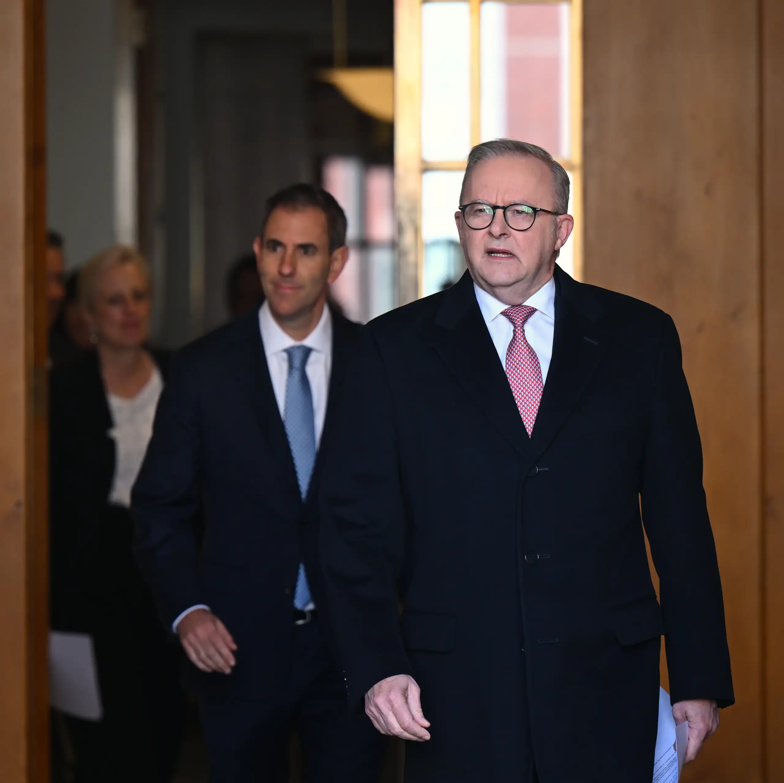 Anthony Albanese walks through a door, followed by Jim Chalmers