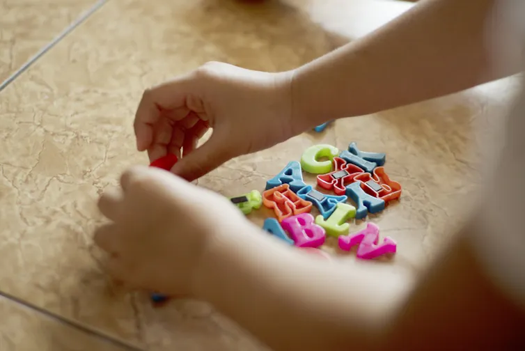 Un enfant manipule des lettres en plastique pour apprendre à lire
