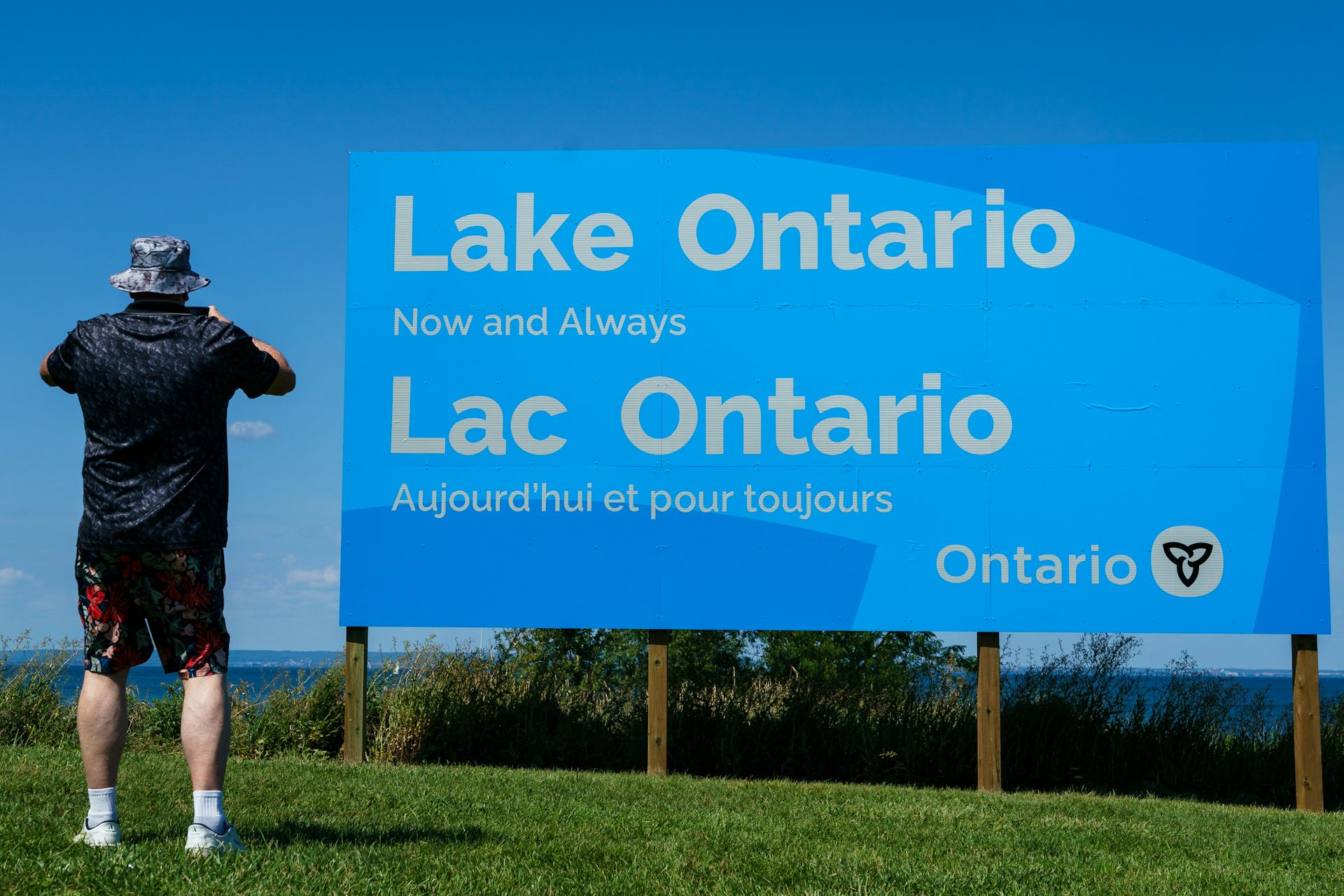 A person takes a photo of a large sign that reads Lake Ontario: Now and always