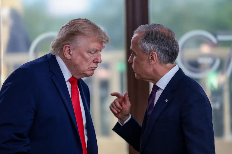 Le président américain Donald Trump écoute le premier ministre canadien Mark Carney, qui un doigt levé