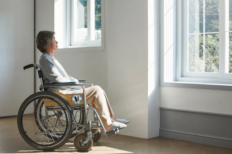 Elderly woman in wheelchair stares out the window