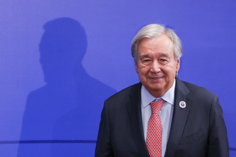 A man in a suit stands in front of a large shadow.
