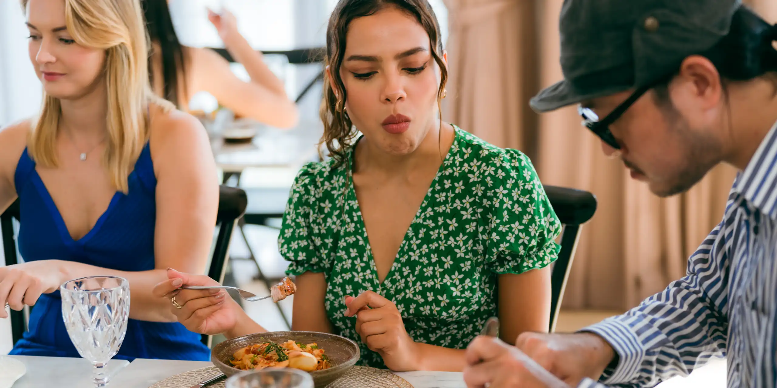 A woman is pictured looking at the person next to her at the dining table as they share a meal together.