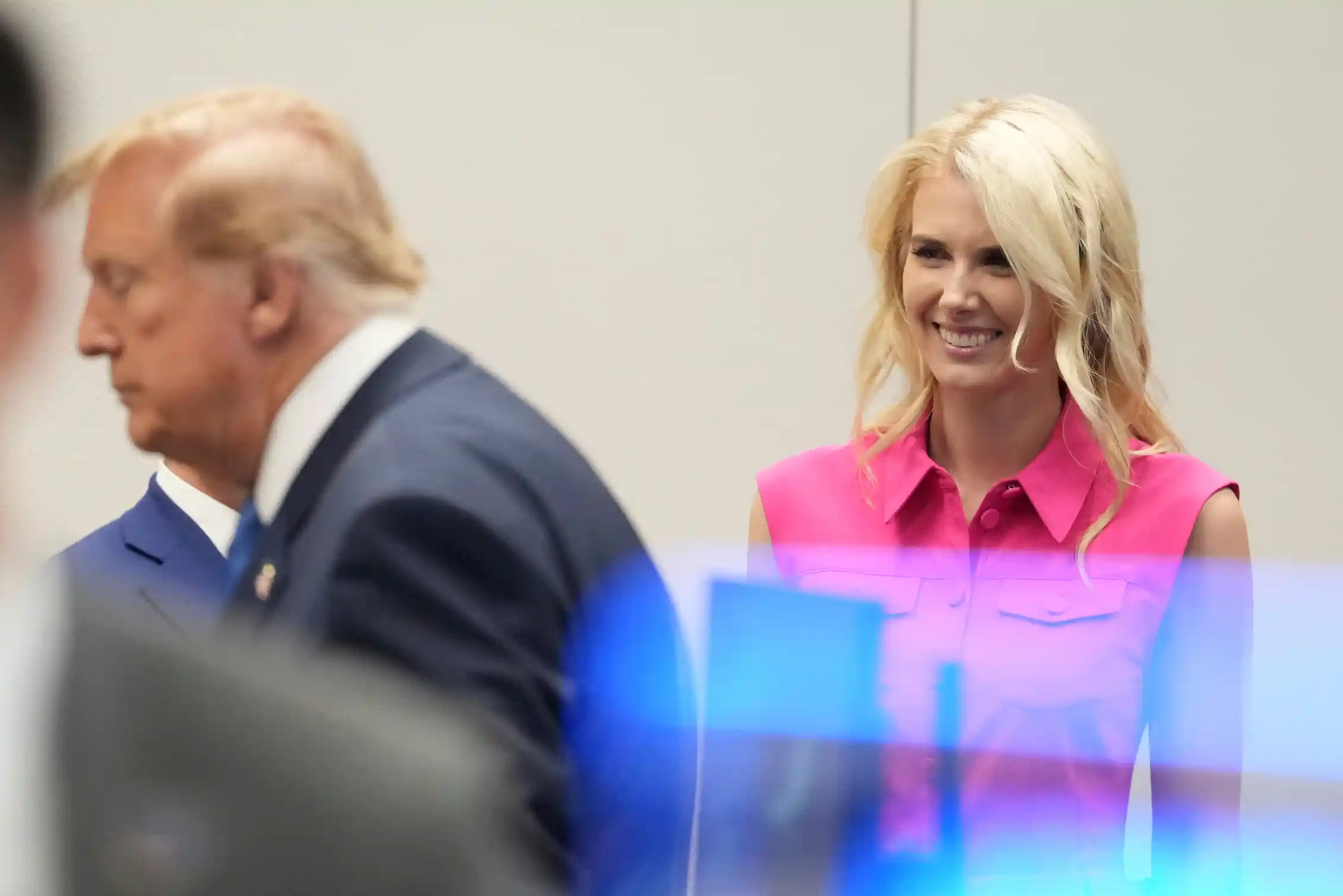 Natalie Harp smiles as she stands behind President Donald Trump, seen in profile