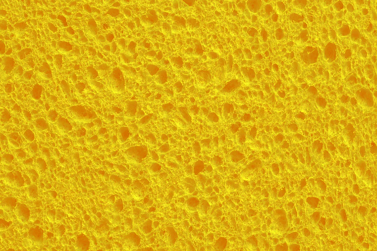 Yellow kitchen or bath sponge, close-up, with holes
