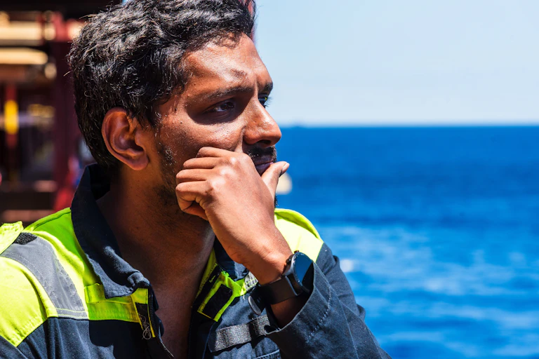 Lonely seafarer on board of the cargo ship, he is looking into the open sea thinking about his home and family.