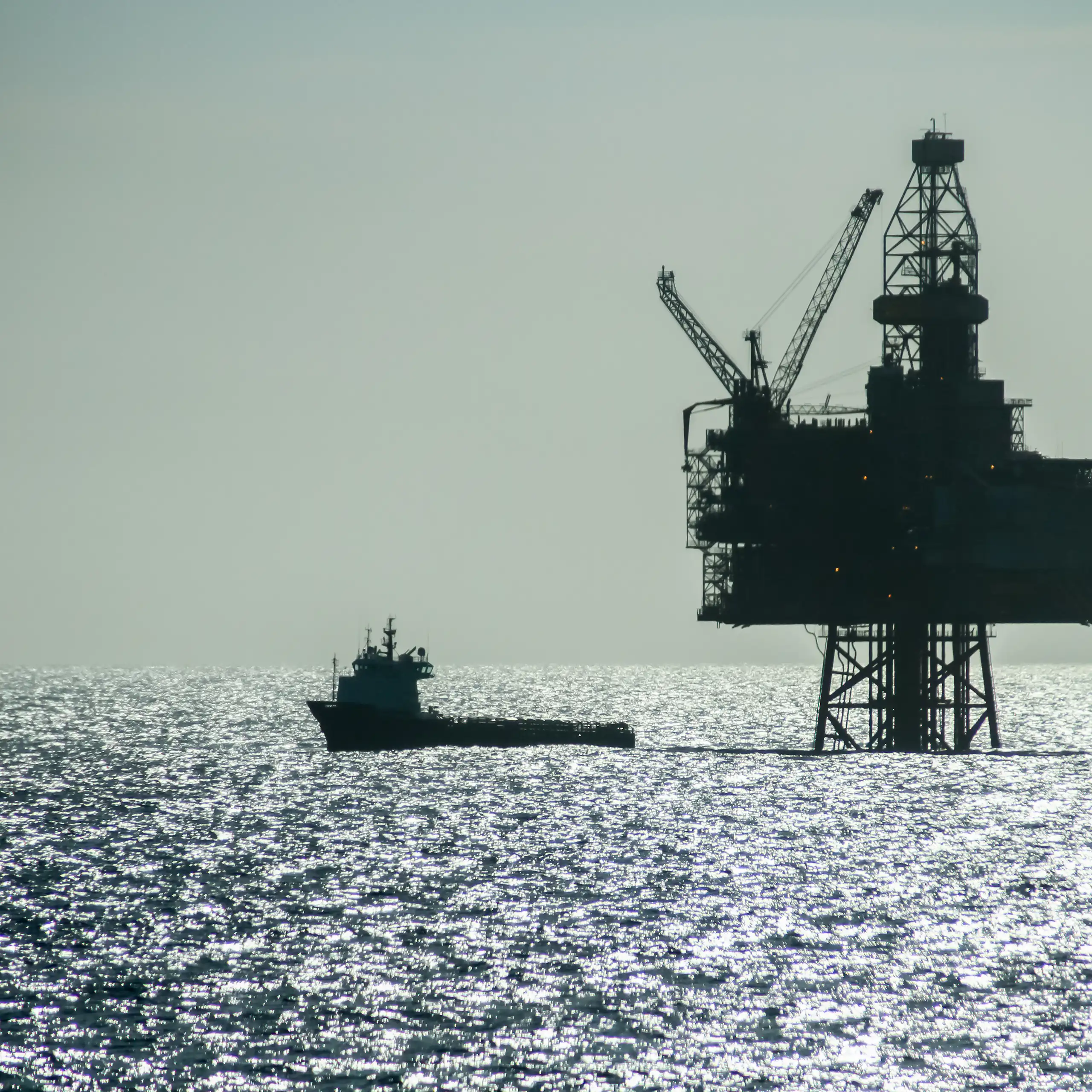 silhouette of ship and oil platform in sea