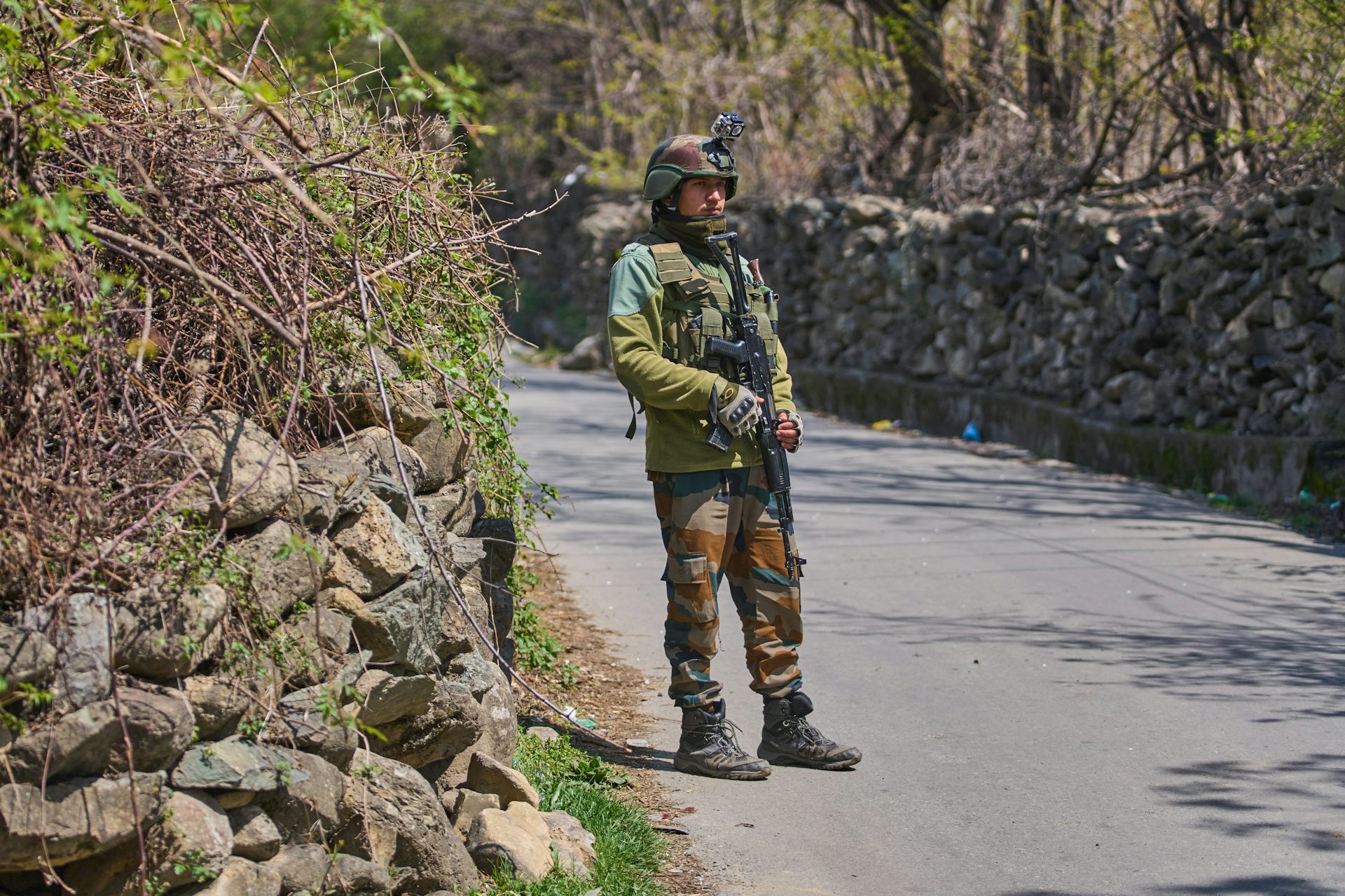 An armed soldier stands on a road.