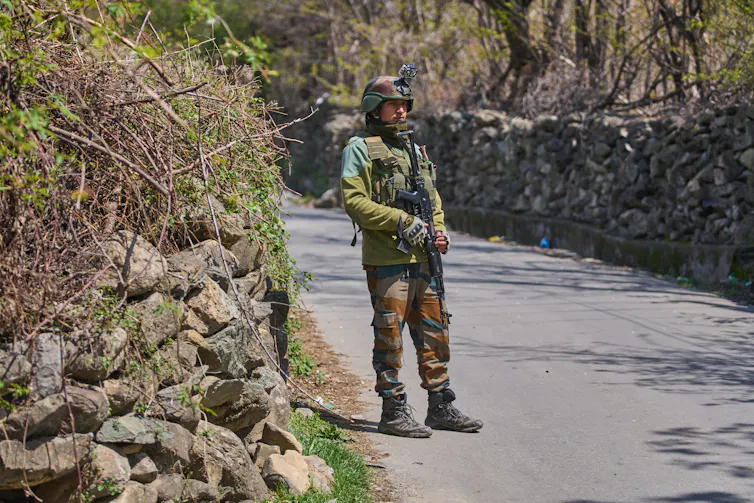 An armed soldier stands on a road.