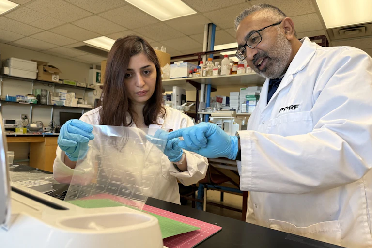 Une femme et un homme en blouse de laboratoire examinent un appareil technologique