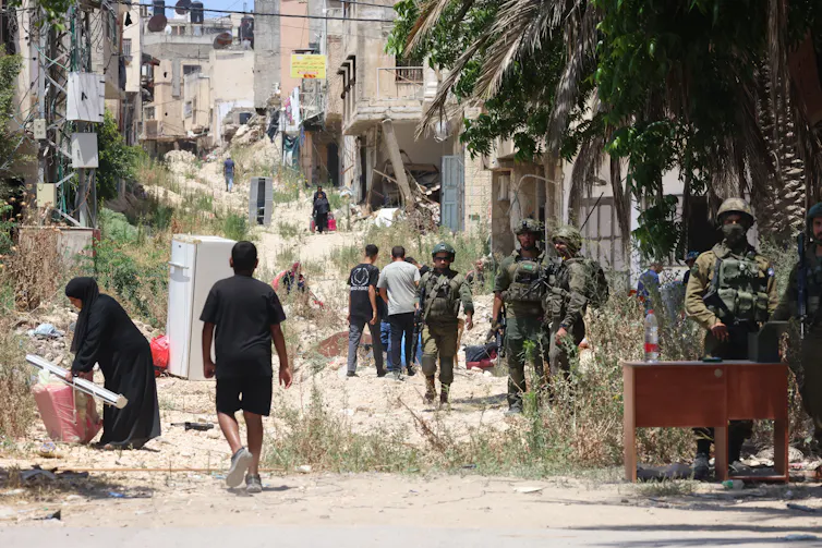 Israeli troops stand guard in a refugee camp for Palestinians.