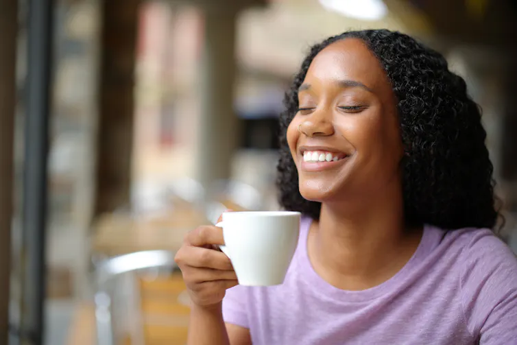 Woman smiles while drinking a cup of tea