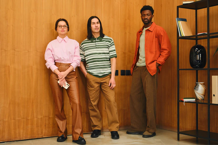 Three young people standing together indoors.