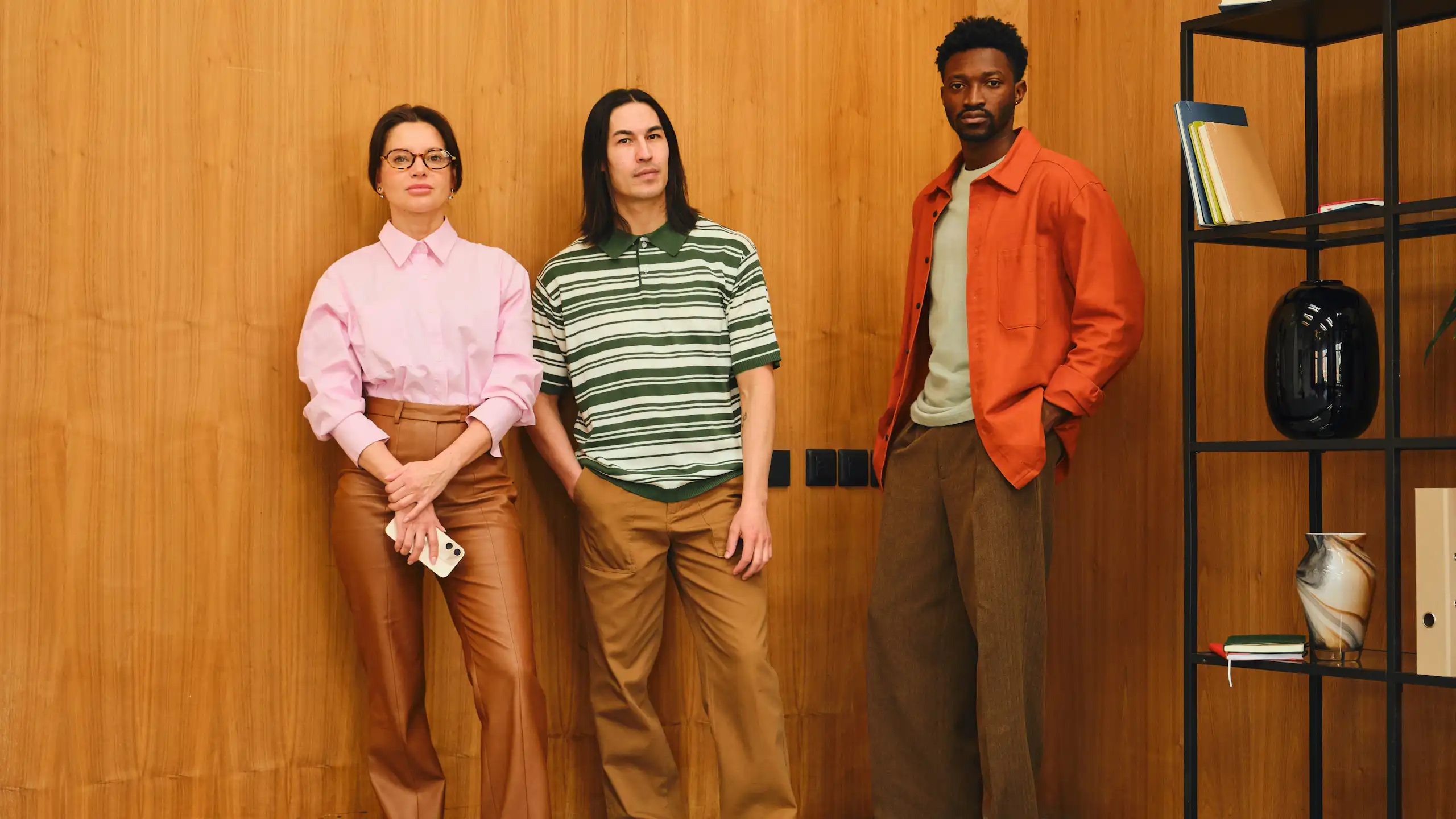 Three young people standing together indoors.