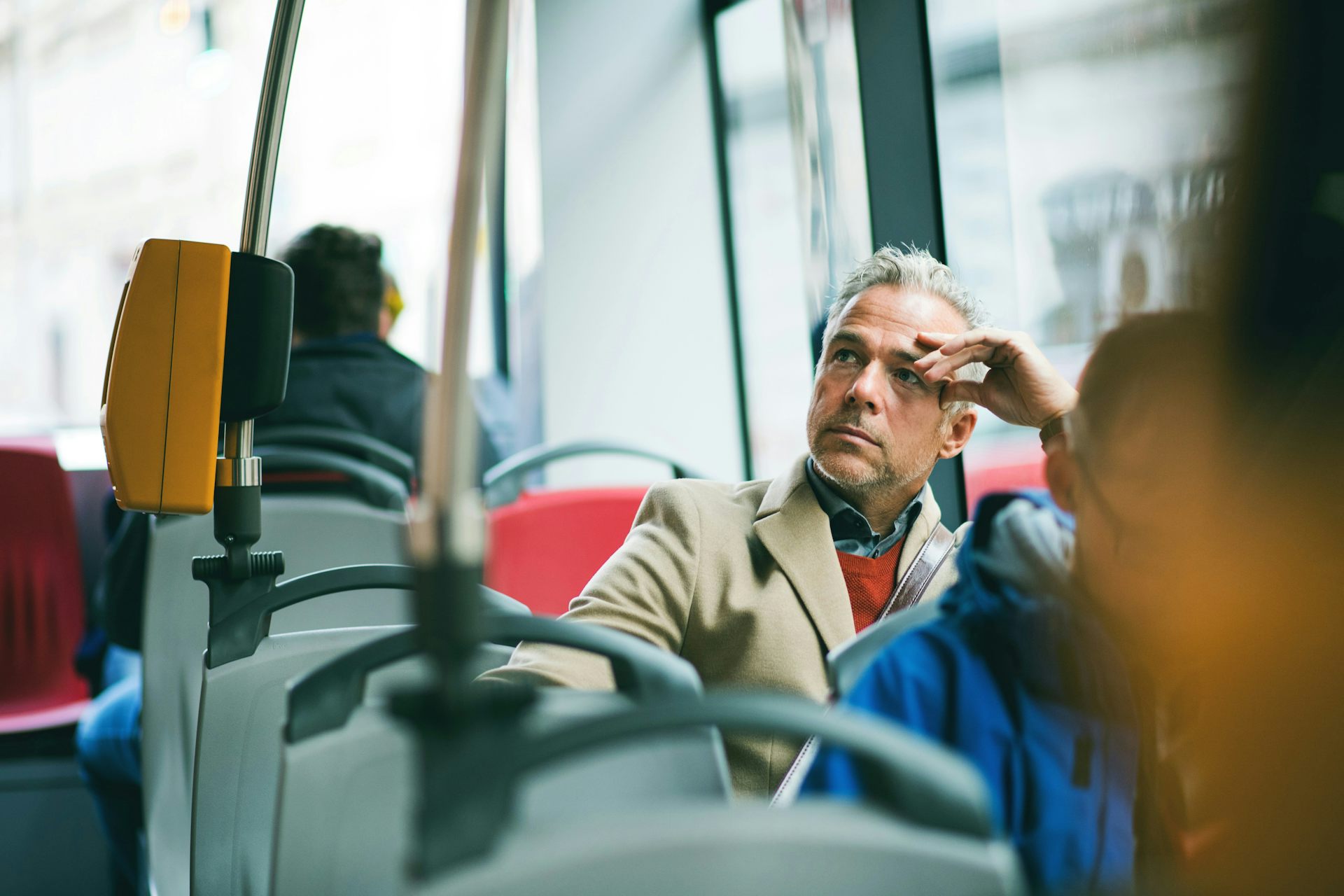 A man on a bus looking away from the window