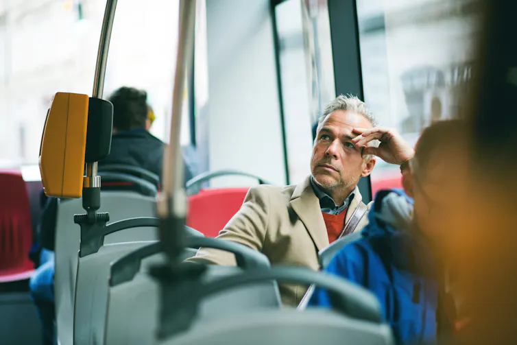 A man on a bus looking away from the window