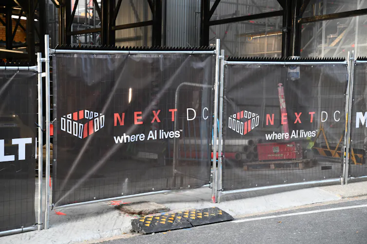 A building fence with nextdc logo and the words where AI lives.