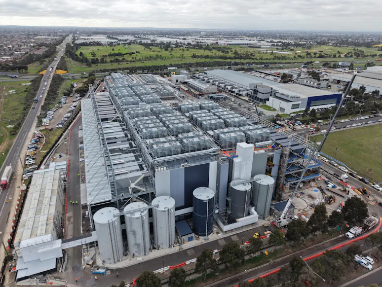 A large grey building with cylindrical tanks in front plane.